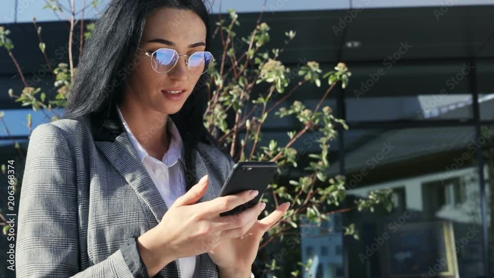 custom made wallpaper toronto digitalstylish successful woman in grey jacket and sunglasses standing outside using modern smart phone mobile thoughtful serious face tapping display social networking brunette female outdoor portrait