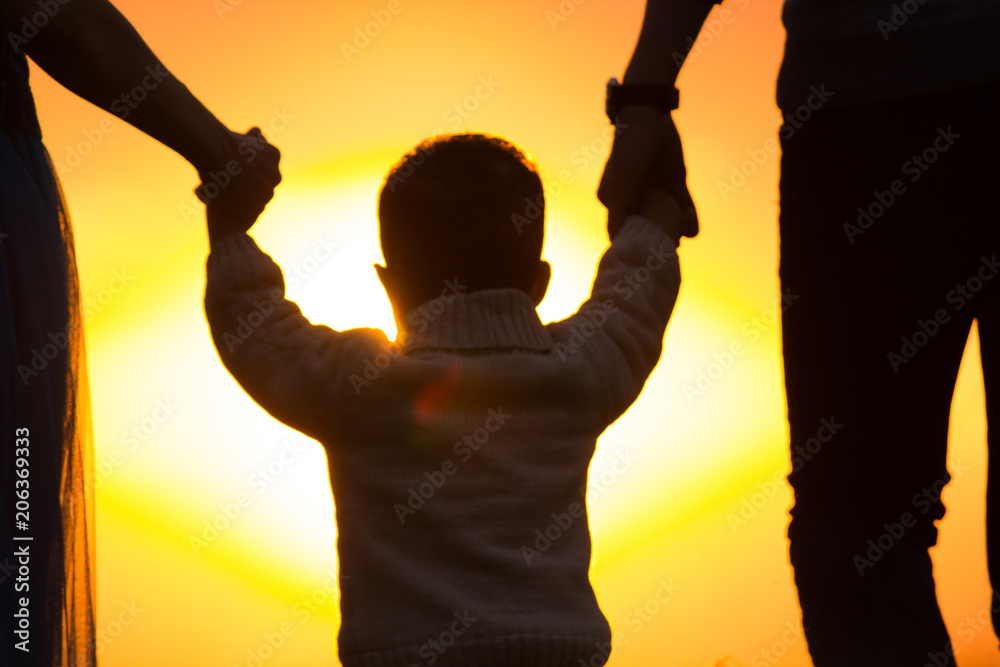 Fototapeta premium The kid is holding hands of parents in the sun