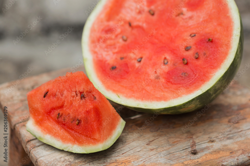 ripe watermelon cut and slices lie on an old wooden stool, rustic style, selective focusing