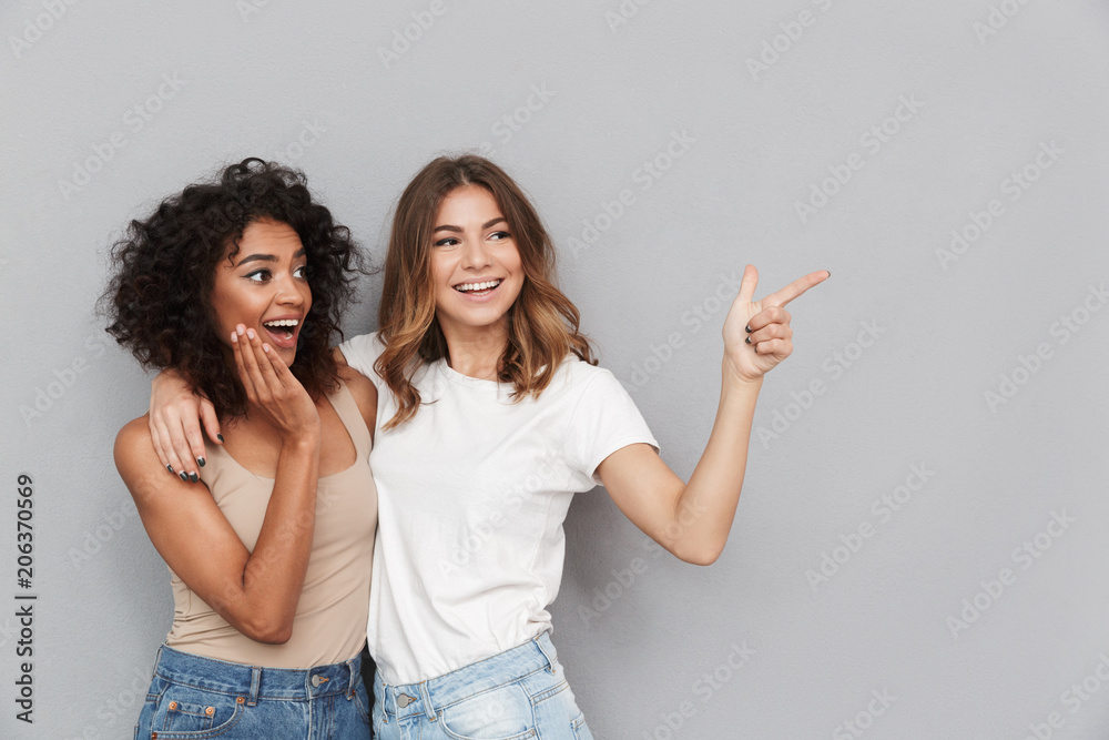 Portrait of two cheerful young women standing together - obrazy, fototapety, plakaty 