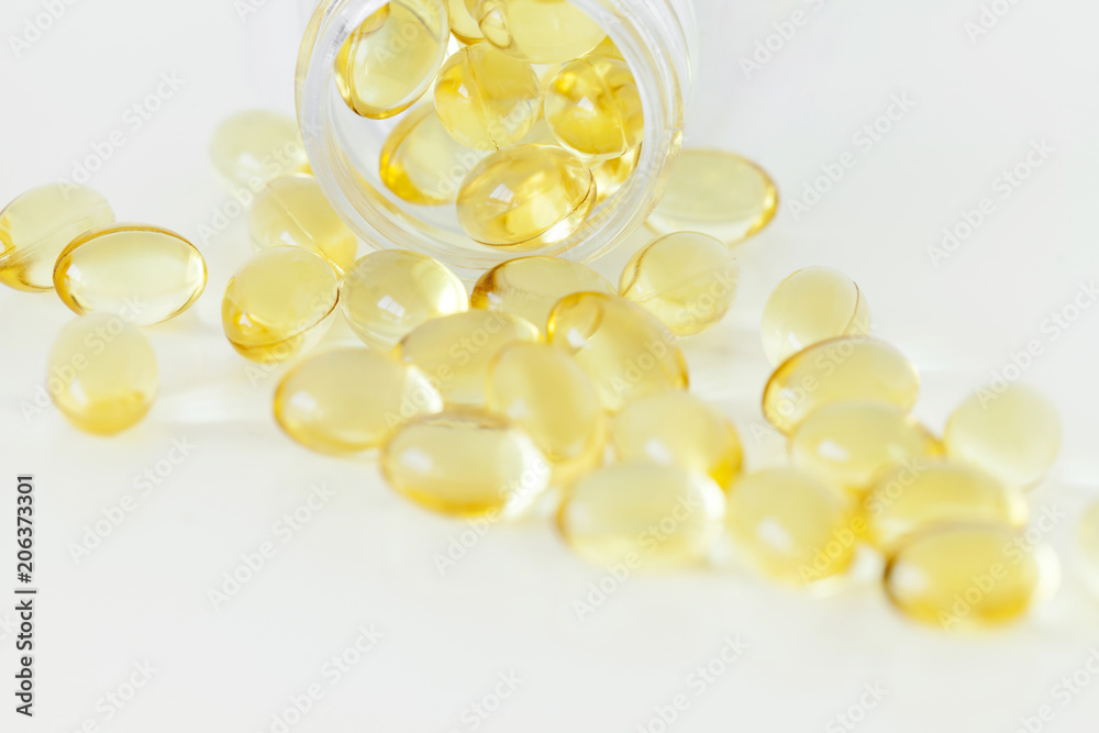 Pile of yellow soft-gel pills isolated over the white background, close-up crop fragment composition Pile of yellow soft-gel pills isolated over the white background, close-up crop fragment composition