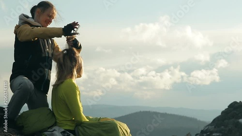 Extreme haircut on top of the cliff. Young male hairdresser doing a haircut for a woman outdoors. A hair salon on top of a rock in the Siberian nature reserve Stolby. Slow motion shot. photo