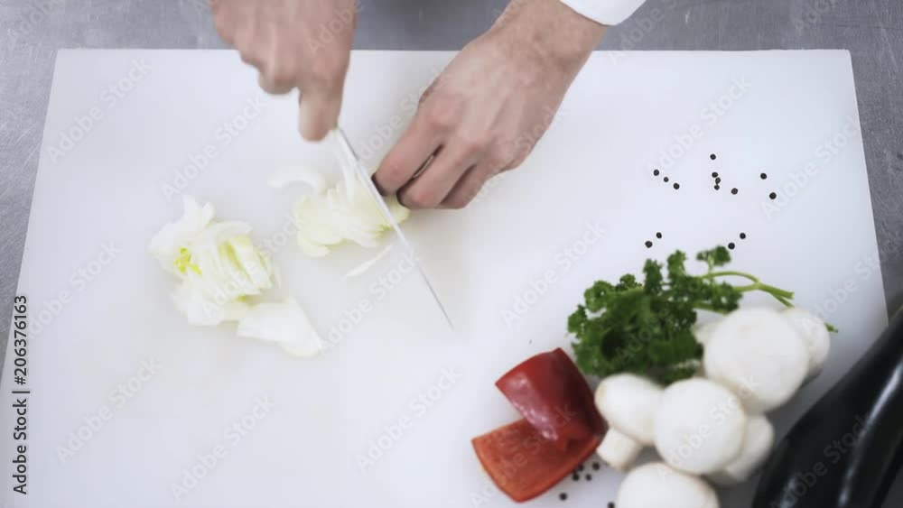 Top view of an unrecognizable chefs hands chopping onion on a cutting board. Concept of high quality food. Locked down real time close up shot Top view of an unrecognizable chefs hands chopping onion on a cutting board. Concept of high quality food. Locked down real time close up shot