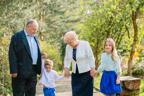 Grandparents with grandchildren relaxing and walking in park. Family and different generation concept.