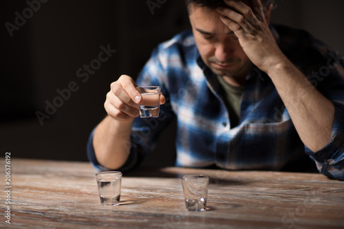 alcoholism, alcohol addiction and people concept - male alcoholic drinking shot at night photo