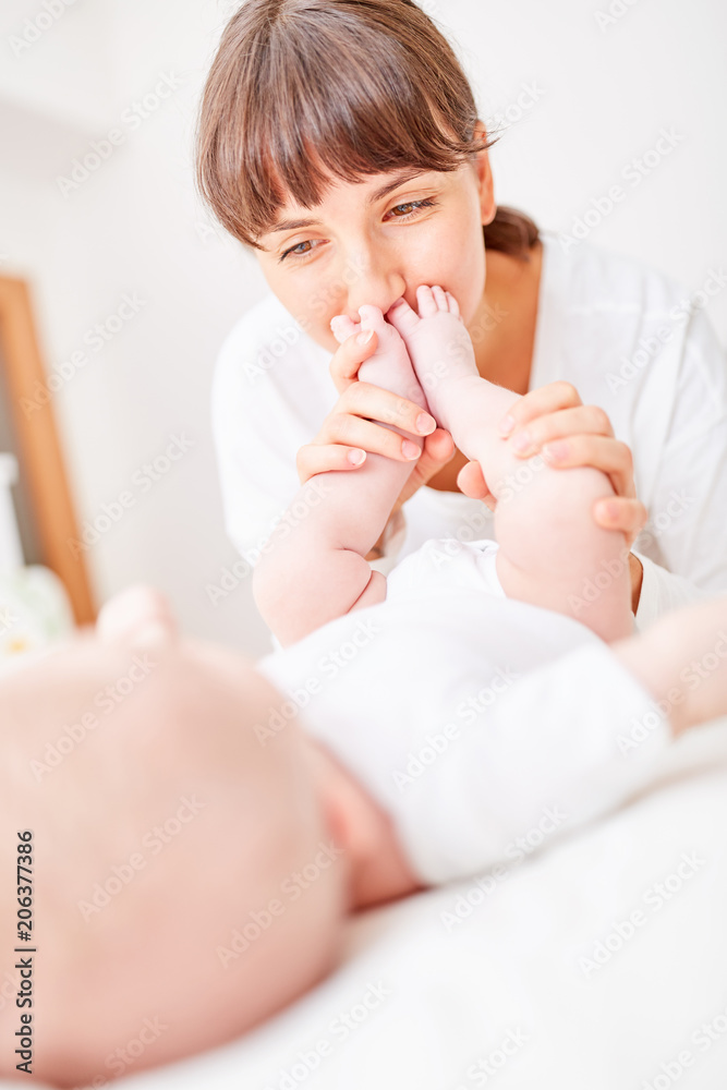 Mutter küsst liebevoll die Füße ihres Babys Mutter küsst liebevoll die Füße ihres Babys