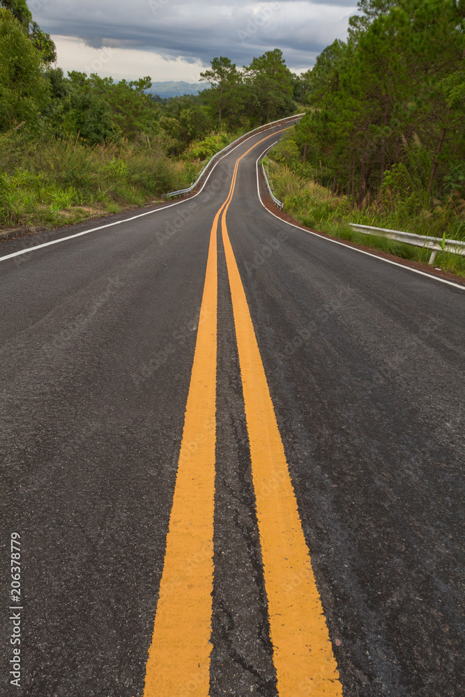 Beautiful mountain asphalt road with curve and double yellow line ,  road runs along the edge of the forest in chiang mai, Thailand