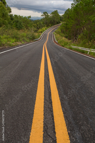Beautiful mountain asphalt road with curve and double yellow line , road runs along the edge of the forest in chiang mai, Thailand
