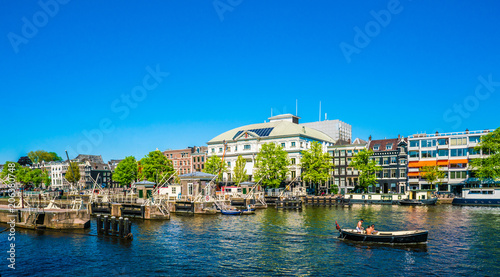 Amsterdam, May 7 2018 - view on the river Amstel filled with small boats and the Carre theater in the background on a summer day