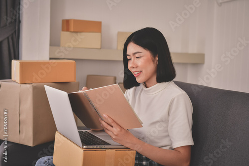 Sme business concept. Young Asian people are packing their packages.Delivery business  Small and Medium Enterprise (SMEs). Young man is working in the house.Young Owner Start up for Business Online. © S photographer
