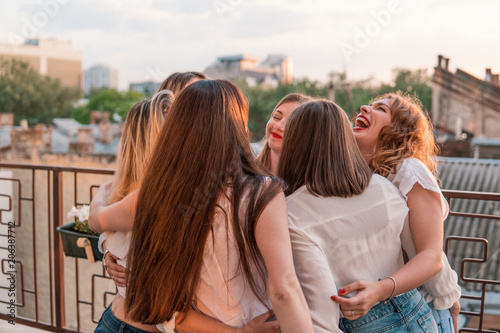 Girls Party. Beautiful Women Friendship on the balcony or roof At Bachelorette Party during sunset. They are hugging