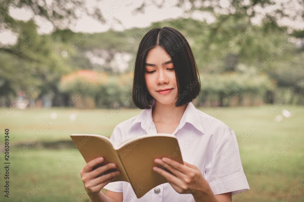 Education Concepts. Beautiful student reading books in the park. Beautiful girl are relaxing in the park. Young student are happy to read. Young student love to study. Education of Asian Women. Education Concepts. Beautiful student reading books in the park. Beautiful girl are relaxing in the park. Young student are happy to read. Young student love to study. Education of Asian Women.