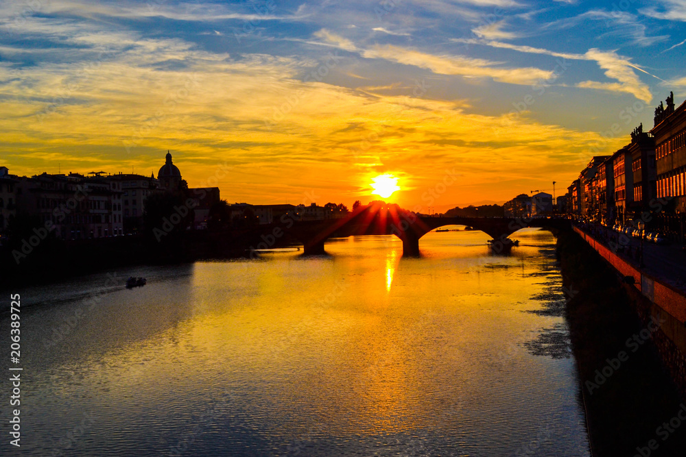 Sunset in Ponte alla Carraia (alla Carraia Bridge) through Arno river and San Frediano in Cestello (Church of Saint Fridianus) at the background. Florence, Italy.