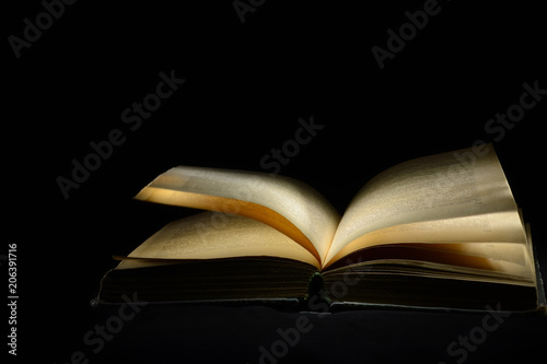 Old open book on a black background