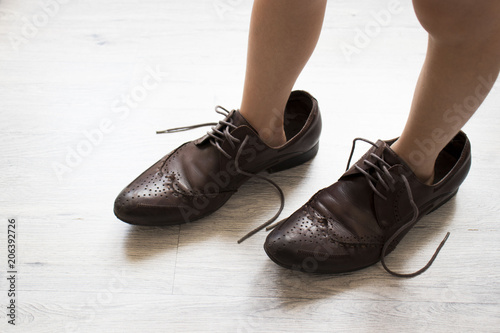 small child, dressed in brown shoes large adult. the child wore dad's shoes