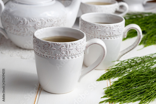 Two cups of horsetail tea with fresh Equisetum arvense plant