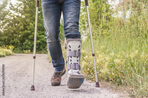 Obraz na płótnie Mann läuft mit einer Orthese und Gehhilfen über einen Feldweg
