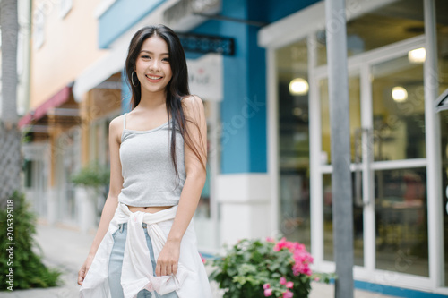 Summer sunny lifestyle fashion portrait of young stylish hipster woman walking on the street, wearing cute trendy outfit