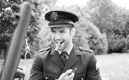 Handsome American WWII GI Army officer in uniform smoking cigar next to Willy Jeep