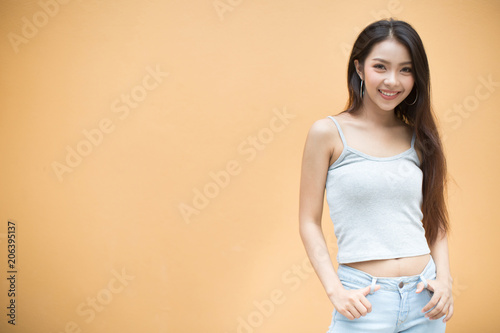 Summer sunny lifestyle fashion portrait of young stylish hipster woman walking on orange background wearing cute trendy outfit