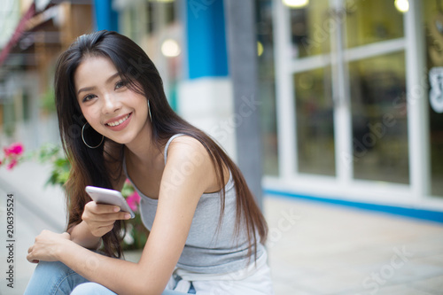 Smiling woman reading message on mobile phone on the street