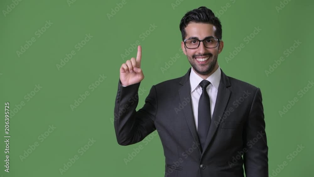 Young handsome bearded Persian businessman against green background Young handsome bearded Persian businessman against green background