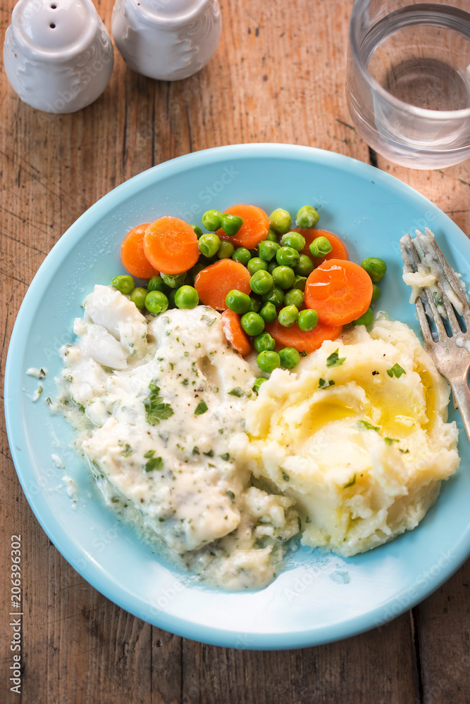 Cod fillet in parsley sauce with mash, peas and carrots. 