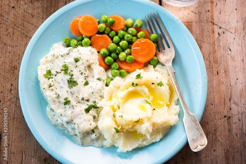 Cod fillet in parsley sauce with mash, peas and carrots. 