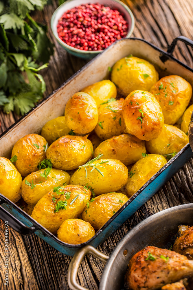 Roasted potatoes with herbs in pan on rustic oak table