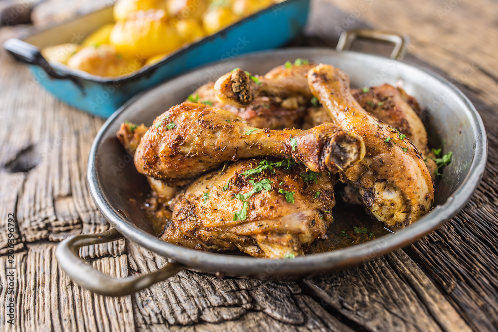 Roasted chicken legs in pan on rustic oak table Roasted chicken legs in pan on rustic oak table