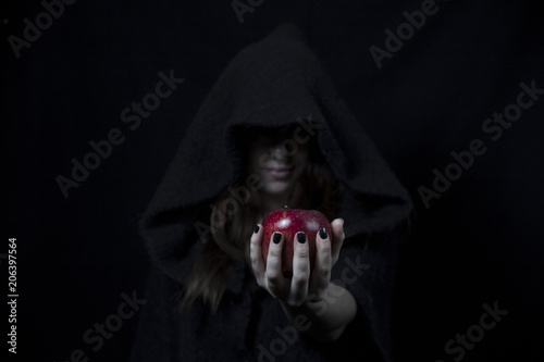 Snow white's red apple in the hand of a black witch with black painted nails photo