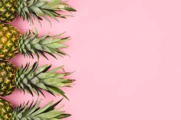 Pineapple fruit side border on a pastel pink background. Top view, flat lay with copy space.