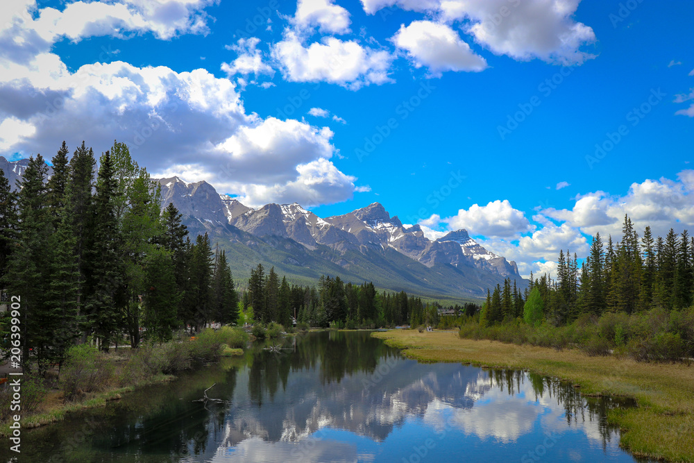 Row of rolling mountains reflecting off the calm waters of a river Row of rolling mountains reflecting off the calm waters of a river