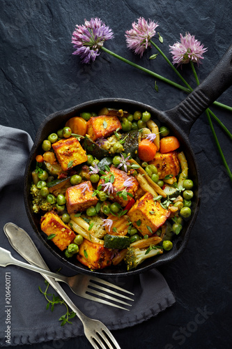 фотографія Tofu with vegetables sprinkled with herbs and edible flowers, top view