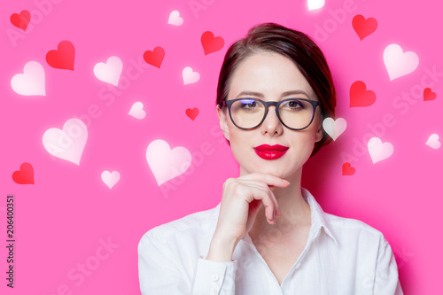Beautiful redhead businesswoman in white shirt with abstract hearts on pink background