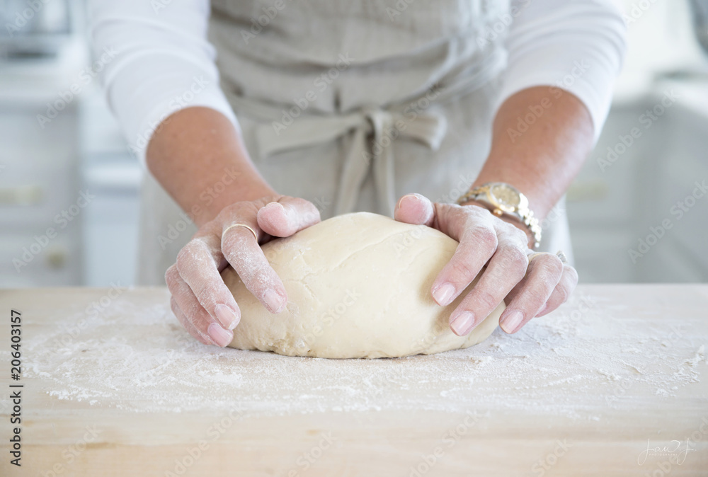 Photograph of a woman’s hands kneading bread dough in the kitchen 