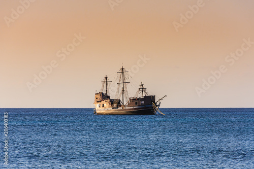 Old wooden sailboat at sunset in the Caribbean sea. Beautiful sky color at twilight. Blue water. Side view.