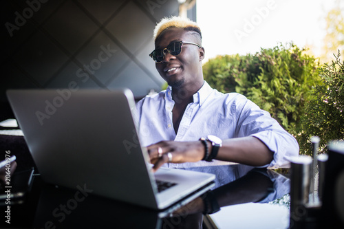 Portrait of young afro american businessman working laptop at cafe teracce photo