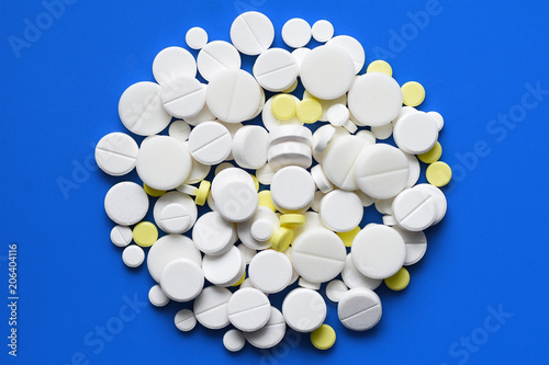 Yellow and white tablets scattered on a blue medical table, background, copy space photo