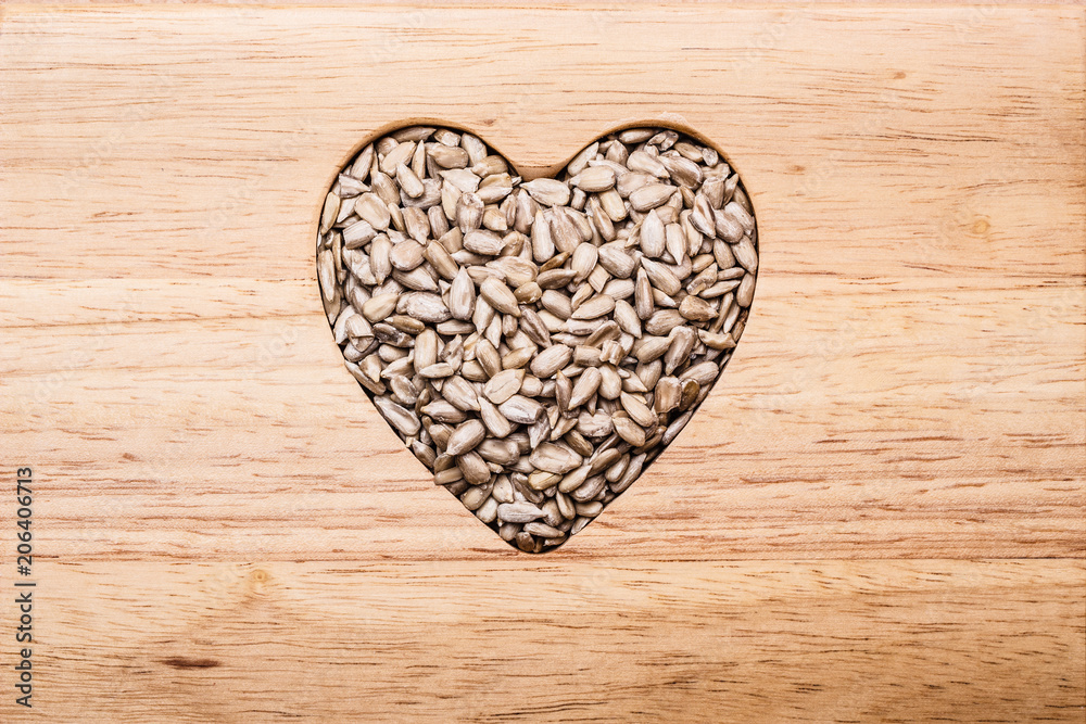 Heart shaped sunflower seeds on wood surface Heart shaped sunflower seeds on wood surface