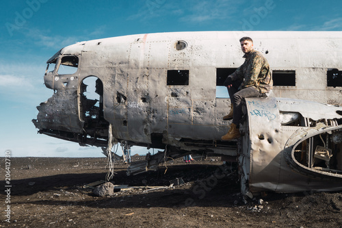 Man sitting on old destroyed airplane photo