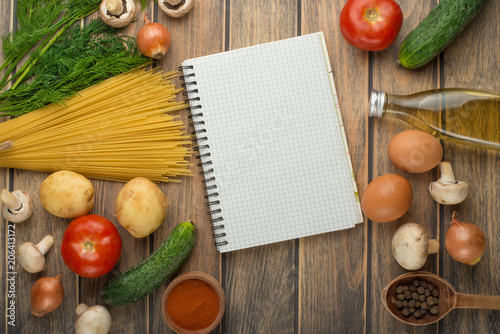 Blank shopping list on paper with vegetables on wooden table