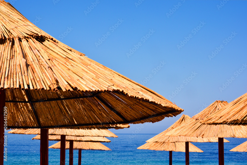Beach Umbrella made of palm leafs on the background of an exotic beach in Montenegro. Tropical background