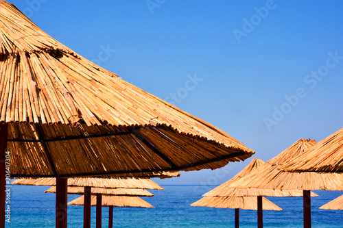 Fototapeta Naklejka Na Ścianę i Meble -  Beach Umbrella made of palm leafs on the background of an exotic beach in Montenegro. Tropical background