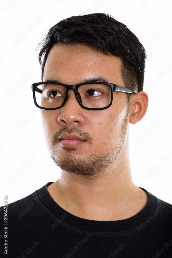 Face of young Asian man thinking while looking at distance and w
