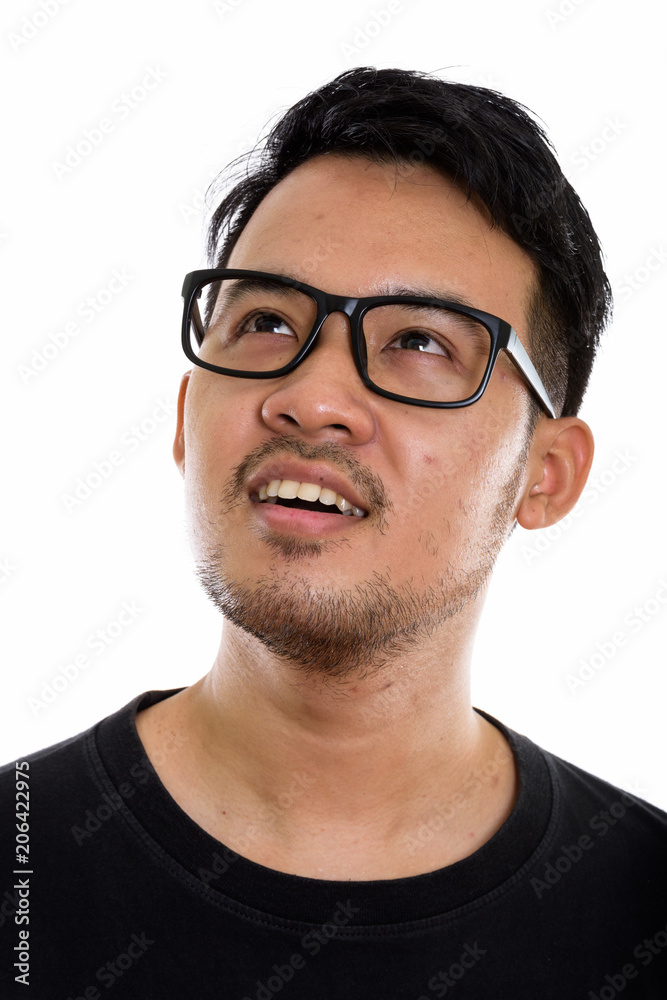 Face of young happy Asian man smiling and thinking while looking Face of young happy Asian man smiling and thinking while looking