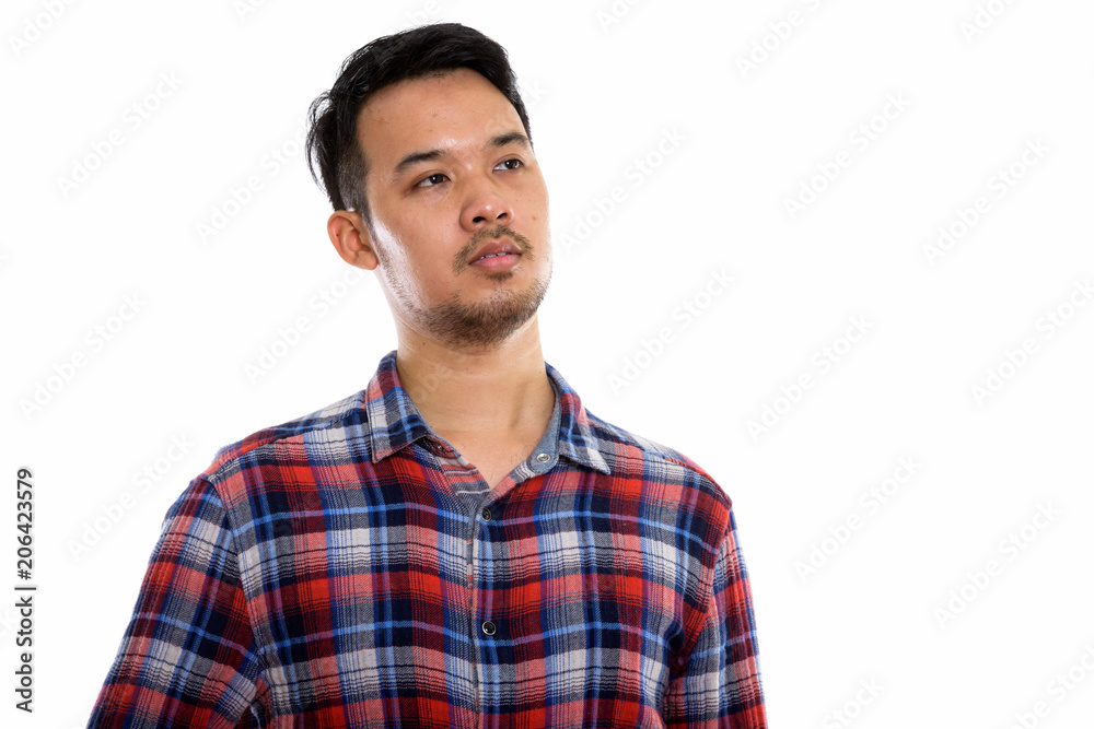 Studio shot of young Asian man thinking while looking up