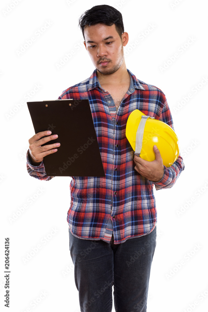 Studio shot of young Asian man construction worker reading on cl Studio shot of young Asian man construction worker reading on cl