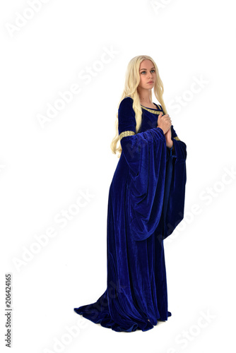 full length portrait of pretty blonde lady wearing a blue fantasy medieval gown. standing pose on white background.