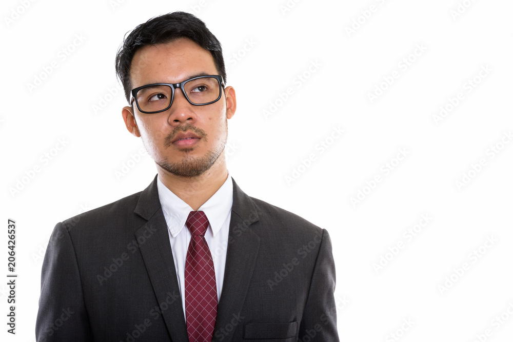 Studio shot of young Asian businessman wearing eyeglasses while Studio shot of young Asian businessman wearing eyeglasses while